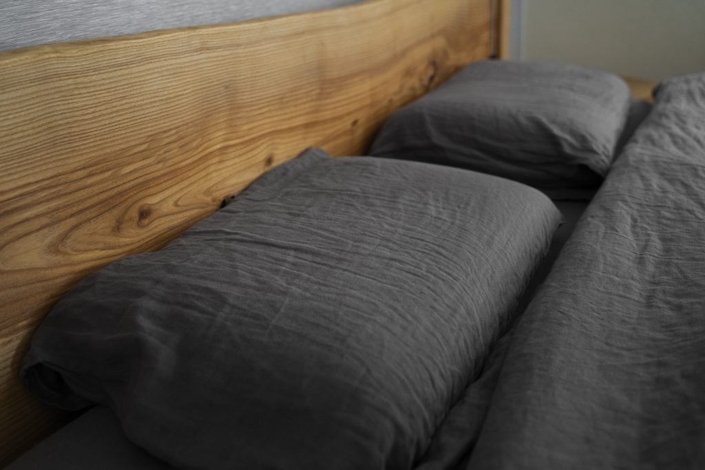 Drewniany zagłówek i ciemna pościel – polski producent łóżek sklep