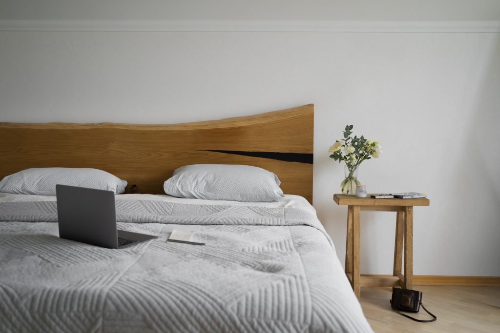 Łóżko drewniane w sypialni z jasną pościelą – polski producent łóżek sklep