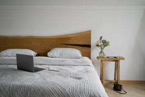 Łóżko drewniane w sypialni z jasną pościelą – polski producent łóżek sklep